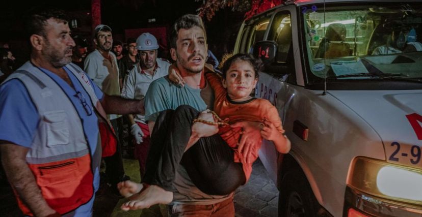 رجل يحمل طفلة أُصيبت جراء غارة استهدفت مدينة خان يونس جنوب القطاع